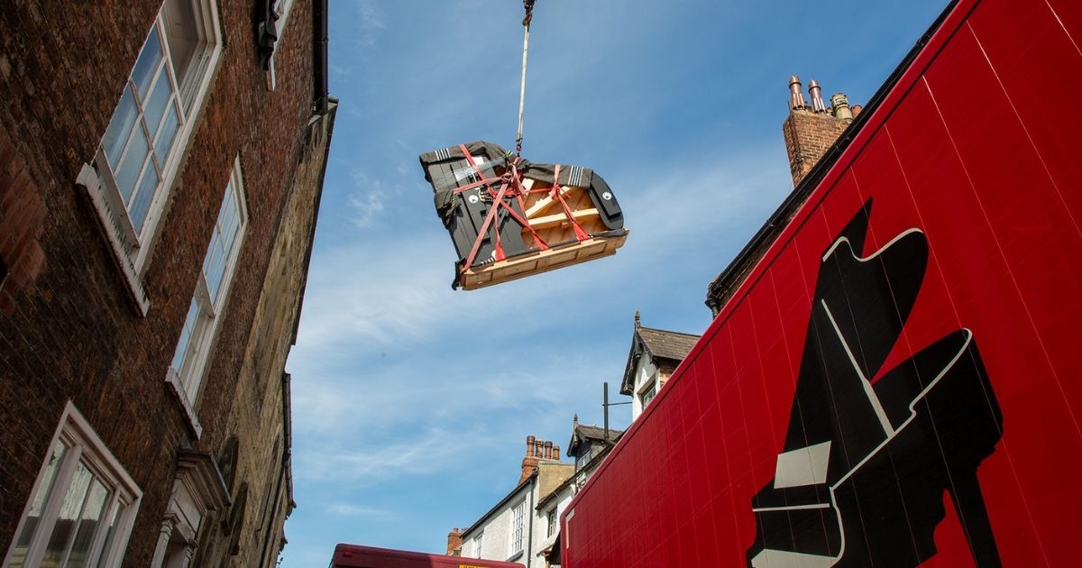 A piano being craned into a building
